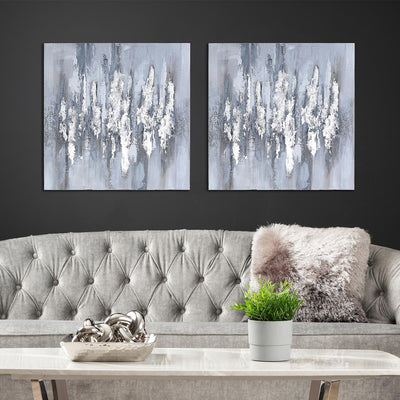 Two abstract wall art pieces above a gray sofa with decorative items.