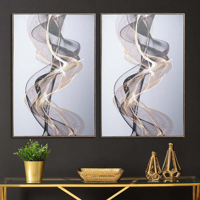Two abstract wall art pieces on a black wall with a gold console table below.