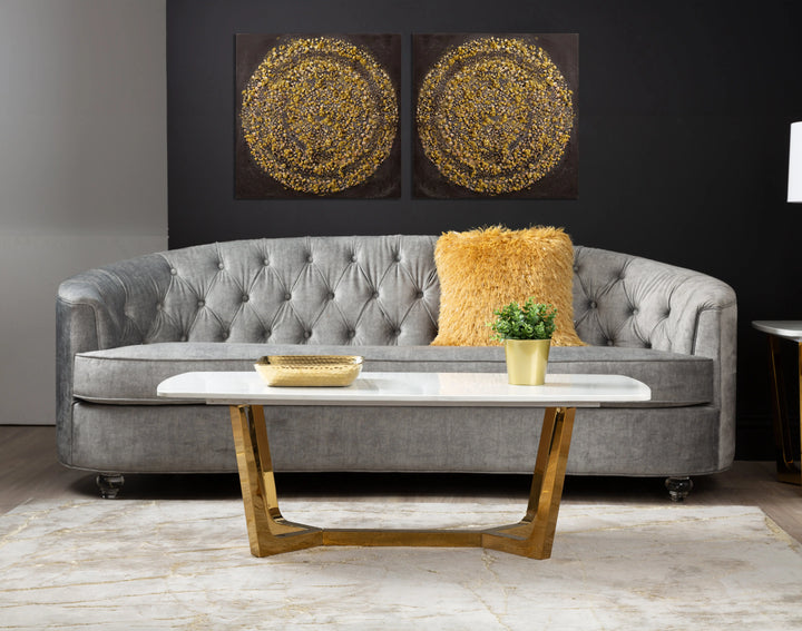 Gray tufted sofa with a marble coffee table and decorative items in a living room setting.